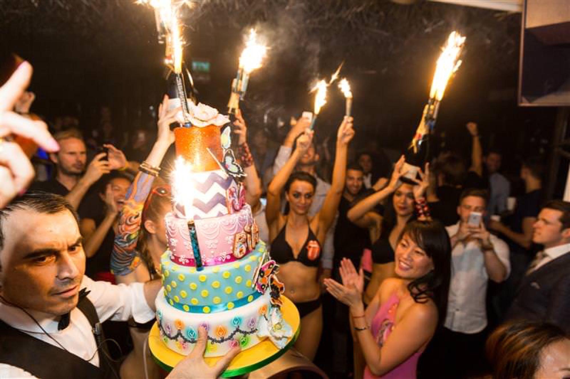 Guests celebrating around a birthday cake